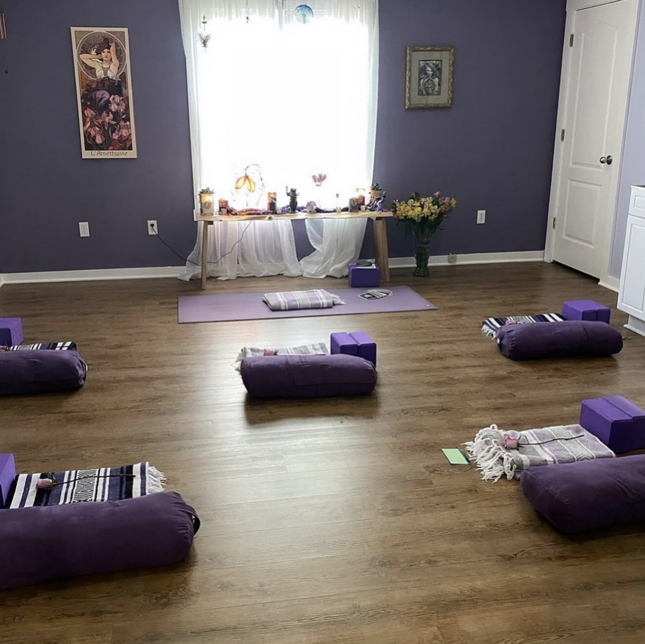 The studio room at Prophecy Tattoo with purple walls and a circle of yoga mats, bolsters and blankets